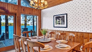A dining area with a wooden table, chairs, and a view of the ocean.