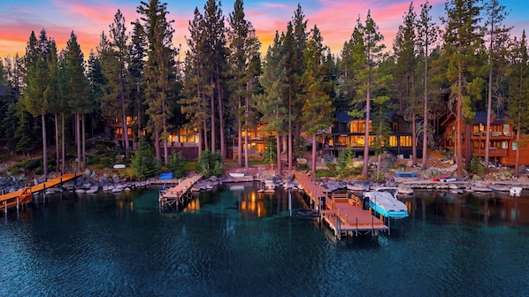 A lakeside property with multiple buildings, docked boats, and a wooden walkway.