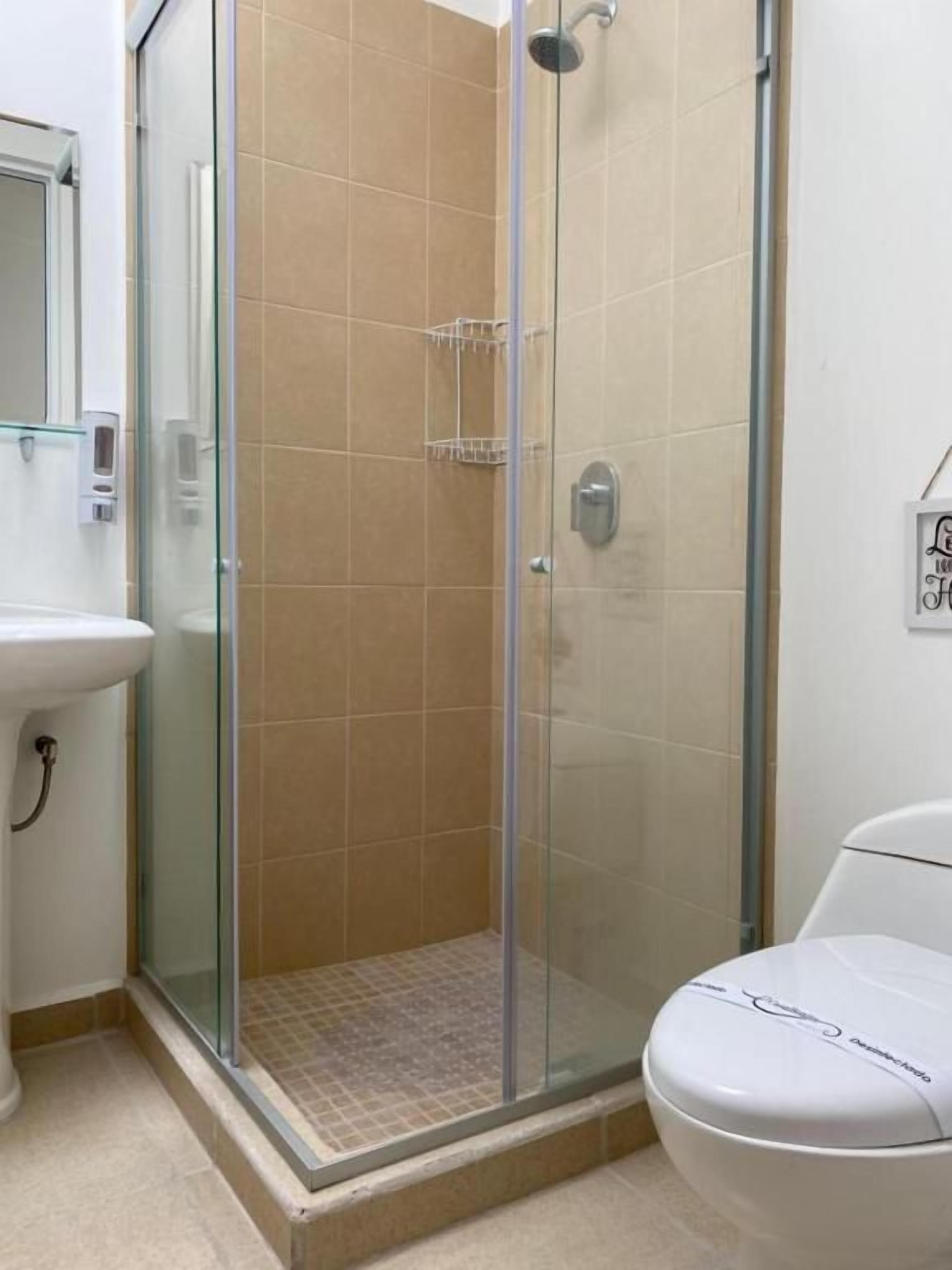 A bathroom with a glass-enclosed shower, a white sink, and a toilet.