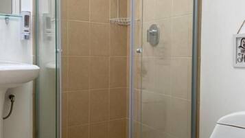 A bathroom with a glass-enclosed shower, a white sink, and a toilet.