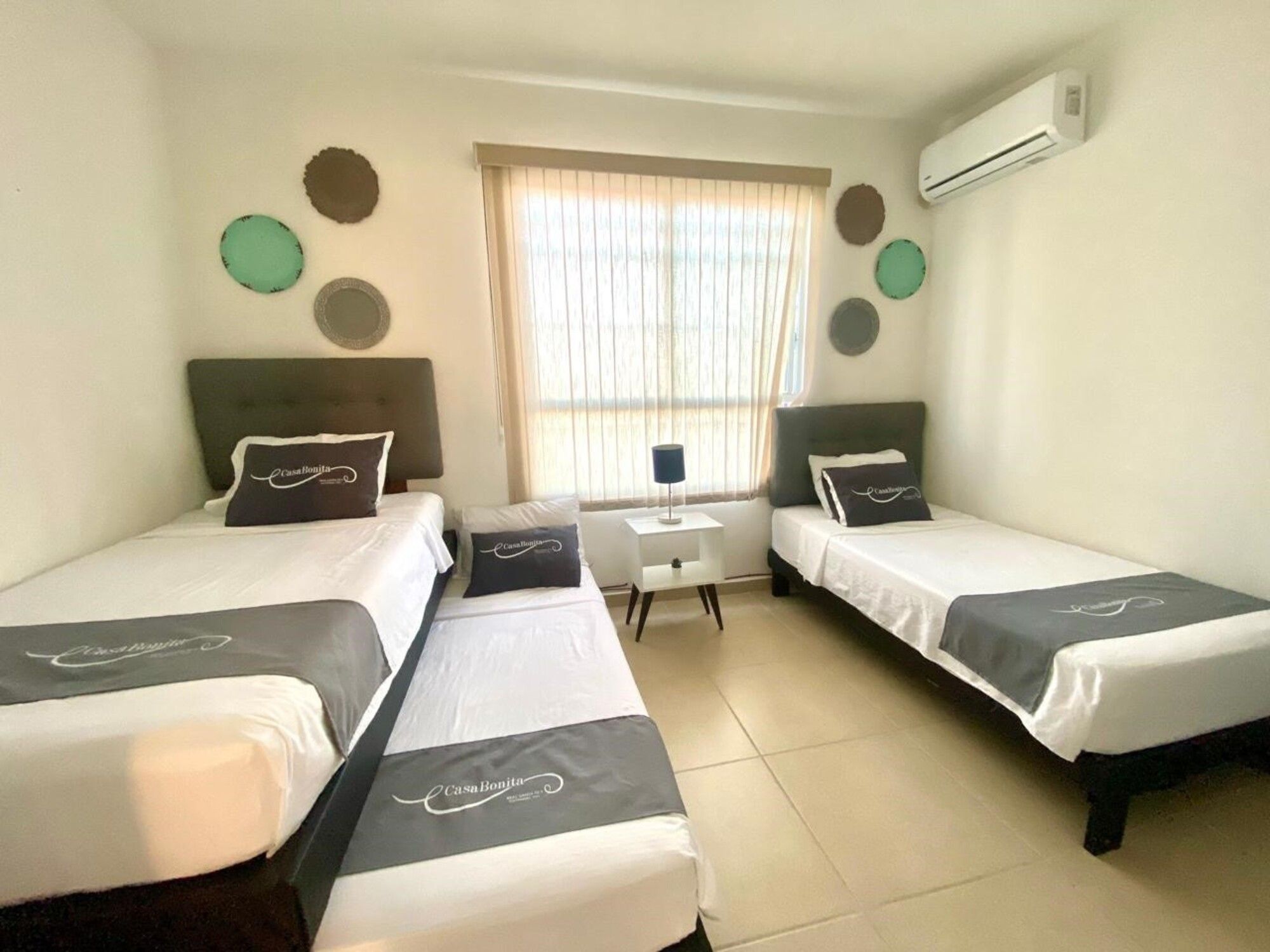 Habitación de hotel con dos camas, un escritorio pequeño y una ventana con persianas.