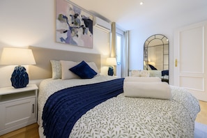 Une chambre à coucher comprenant un lit, deux tables de chevet, une commode, un miroir et un tableau accroché au mur.