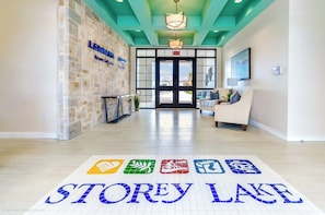 A hotel lobby with a reception desk, a seating area, and a floor with the name 'STOREY LAKE' in blue tiles. - Family Townhouse Near Disney | HeatedPool | Lazy River (Kissimmee)