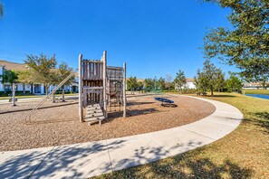 A playground with a wooden climbing structure and a blue swing set. - Family Townhouse Near Disney | HeatedPool | Lazy River (Kissimmee)
