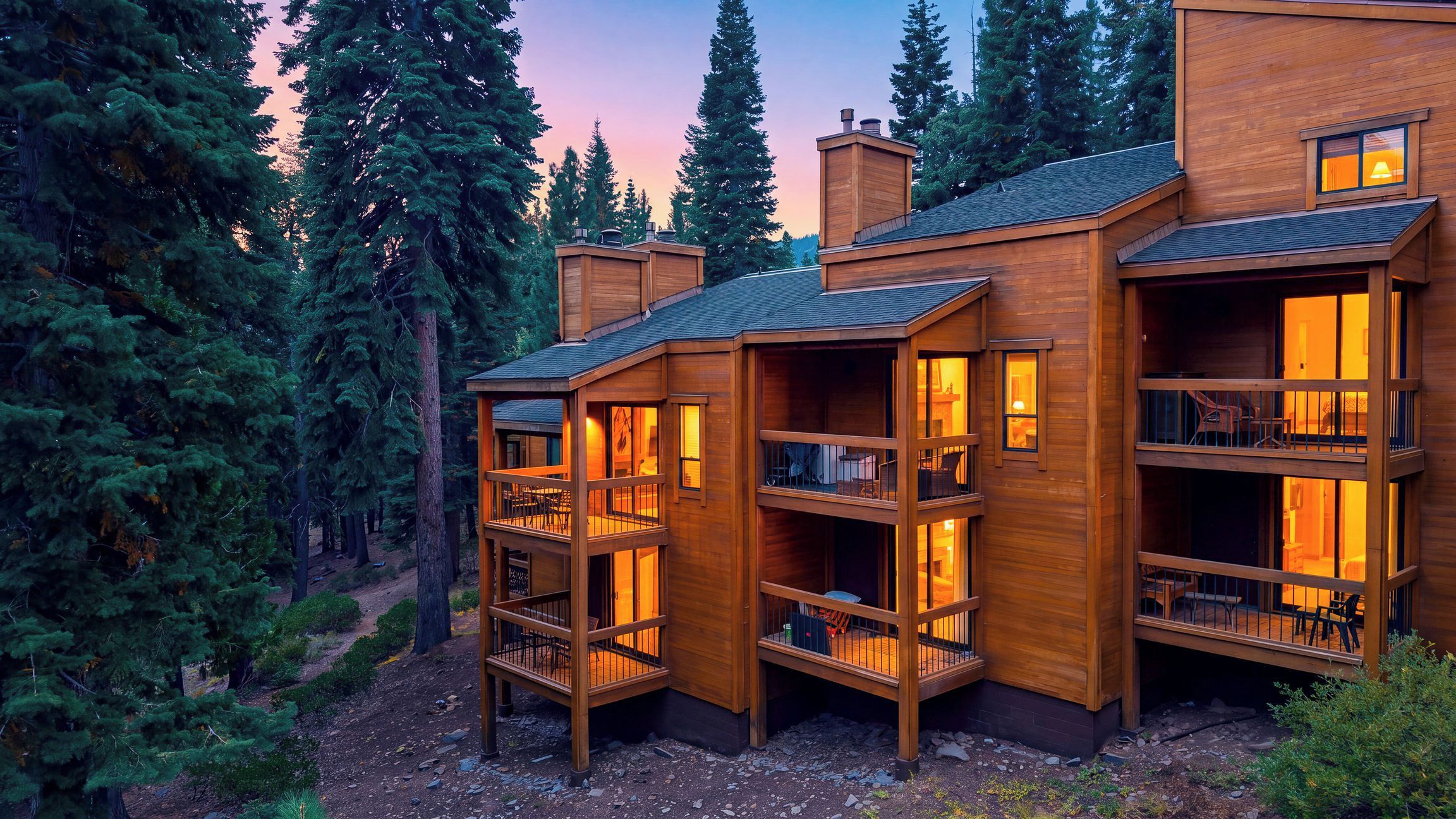 Una cabaña de madera de varios pisos con balcones, rodeada por un bosque denso.
