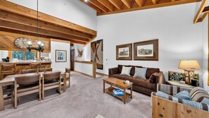 Ein gemütliches Wohnzimmer mit Holzboden, einem braunen Ledersofa, einem Couchtisch und einem Essbereich mit Holztisch und Stühlen.