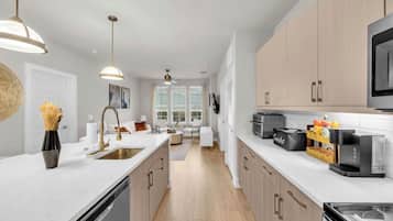 A modern kitchen with white countertops, stainless steel appliances, and wooden cabinets.