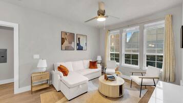 A modern living room with a white sofa, a round coffee table, and a ceiling fan.