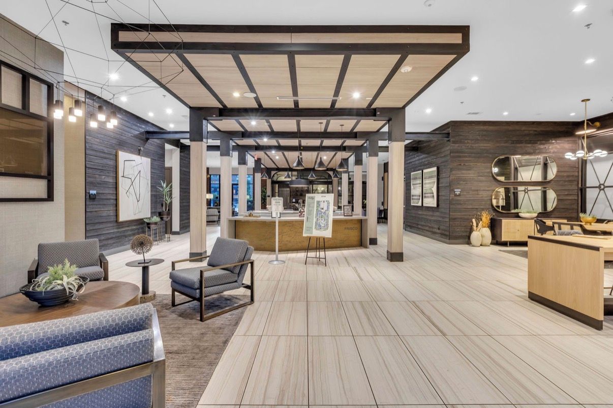 A modern interior with a reception desk, seating area, and a wooden floor.