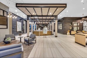 Een modern interieur met een receptiebalie, een zithoek en een houten vloer.