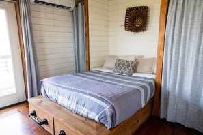 A single bed with a striped blanket, wooden headboard, and a wall-mounted decorative item. - The Cabin With The OK View (Grayson County)