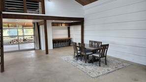 Ein Essbereich mit Tisch und Stühlen, einem gemusterten Teppich und Blick auf eine Garage mit gestapeltem Holz.