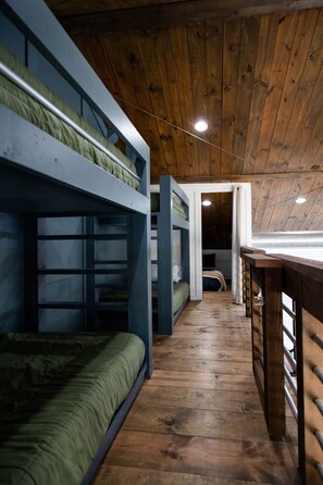 Ein Schlafzimmer mit Etagenbett, Holzboden und geneigter Decke.