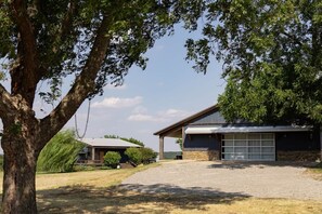 Ein Wohnhaus mit Garage, überdachter Terrasse und einem großen Baum.