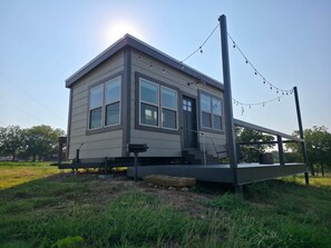 A small, single-story house with a front porch and a deck. - Tiny Home With The OK View (Grayson County)
