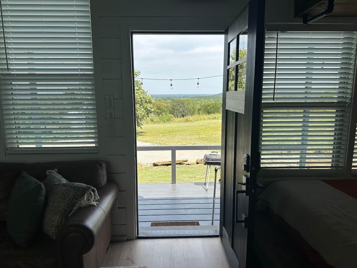 A room with a door leading to an outdoor area, a sofa, and a bed.