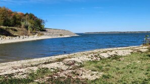 Una spiaggia con acque cristalline, una riva sabbiosa e una zona boscosa sullo sfondo.