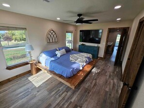 Ein Schlafzimmer mit einem Bett, einem Deckenventilator, einem Fernseher und Blick ins Freie.