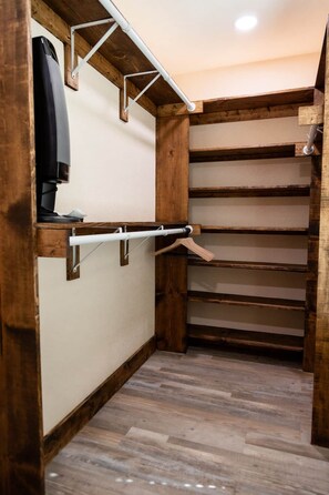 Un armario de almacenamiento con estantes de madera y una barra para colgar.