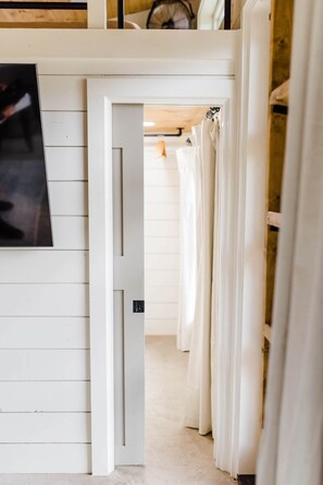 Ein Flur mit einer weißen Tür, einem gerahmten Bild an der Wand und einer Reihe weißer Vorhänge.