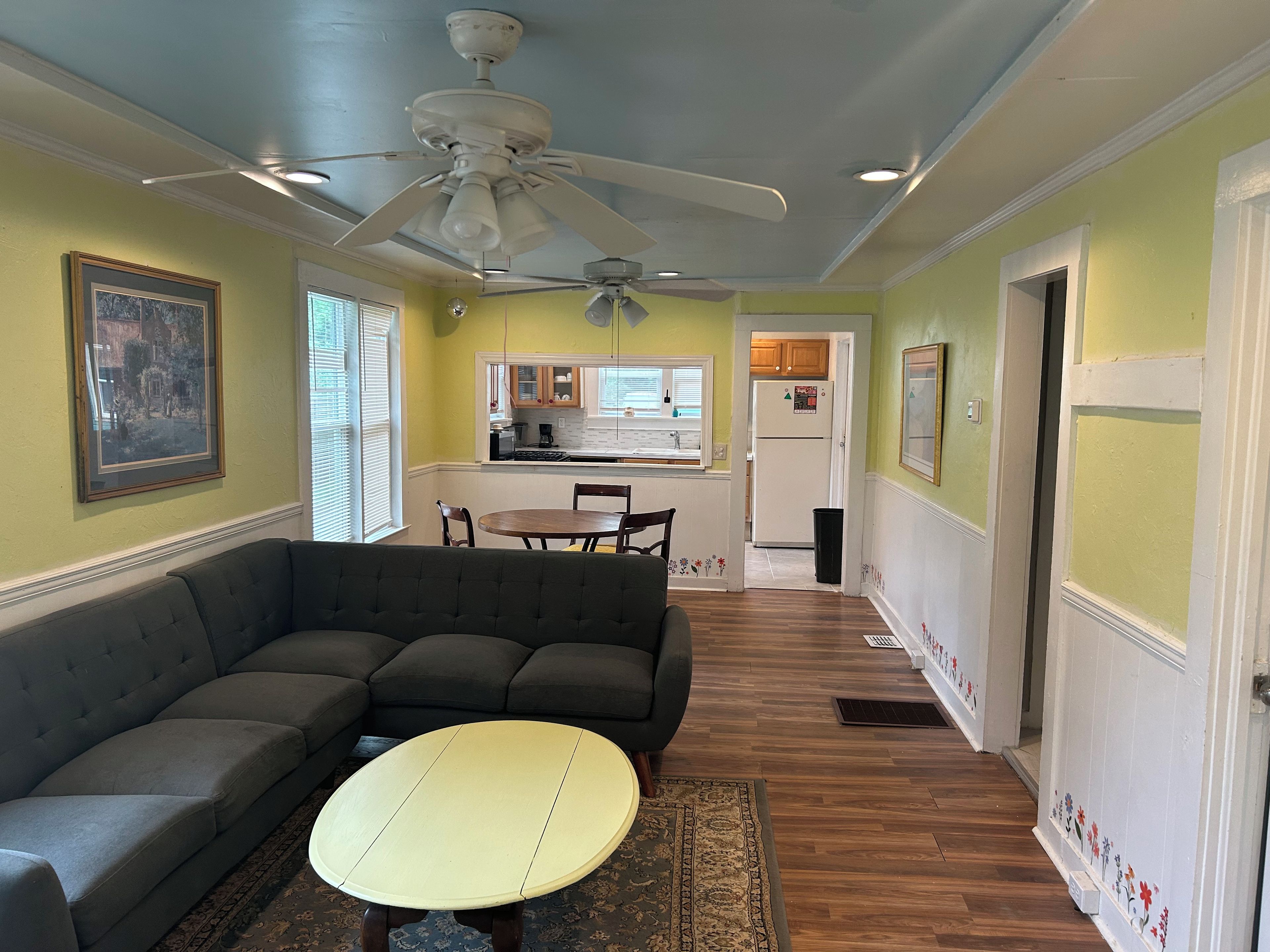 A living room with a sectional sofa, a round coffee table, and a ceiling fan.