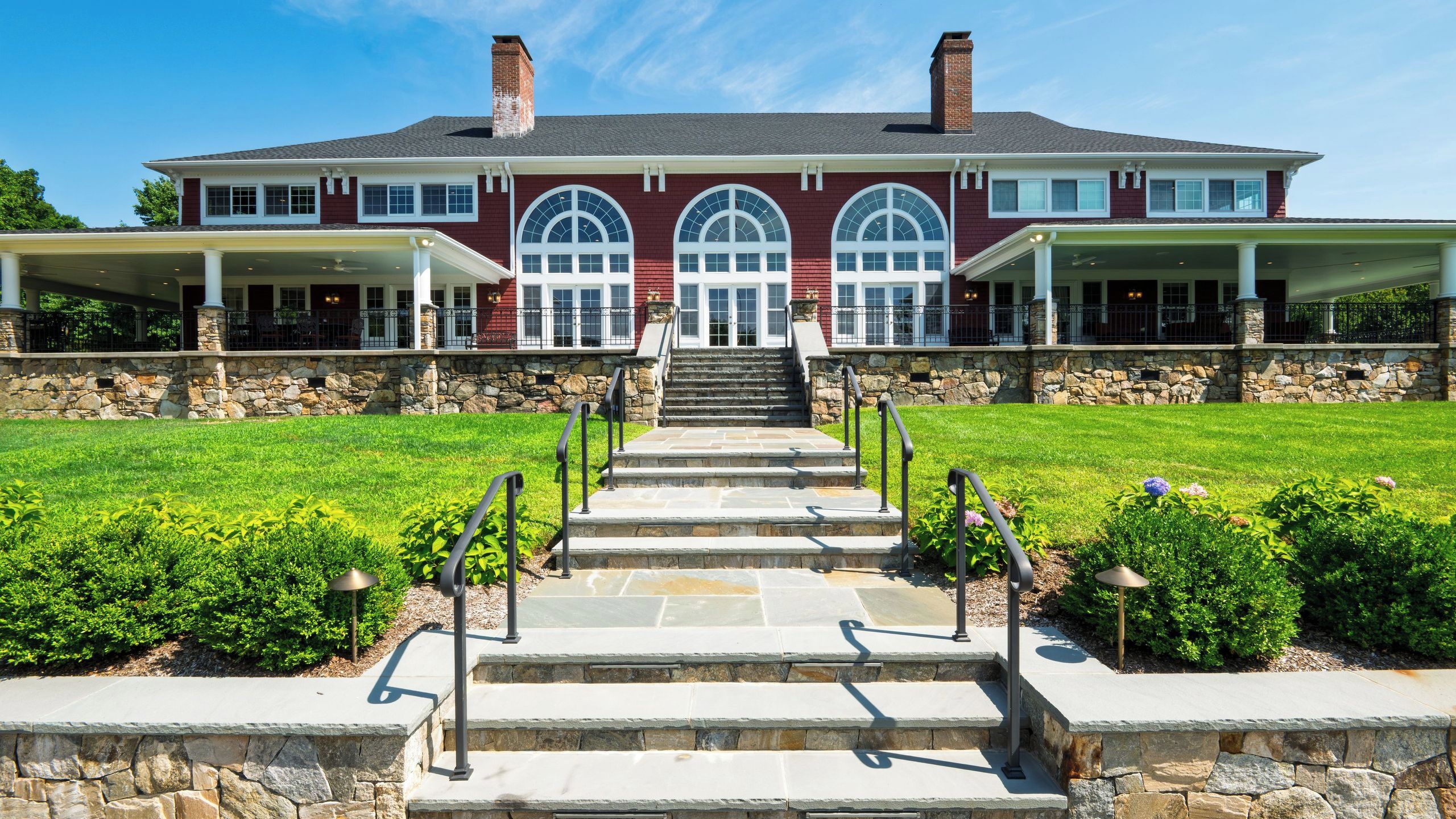 A large, two-story house with a stone facade, a front porch, and a well-maintained lawn.