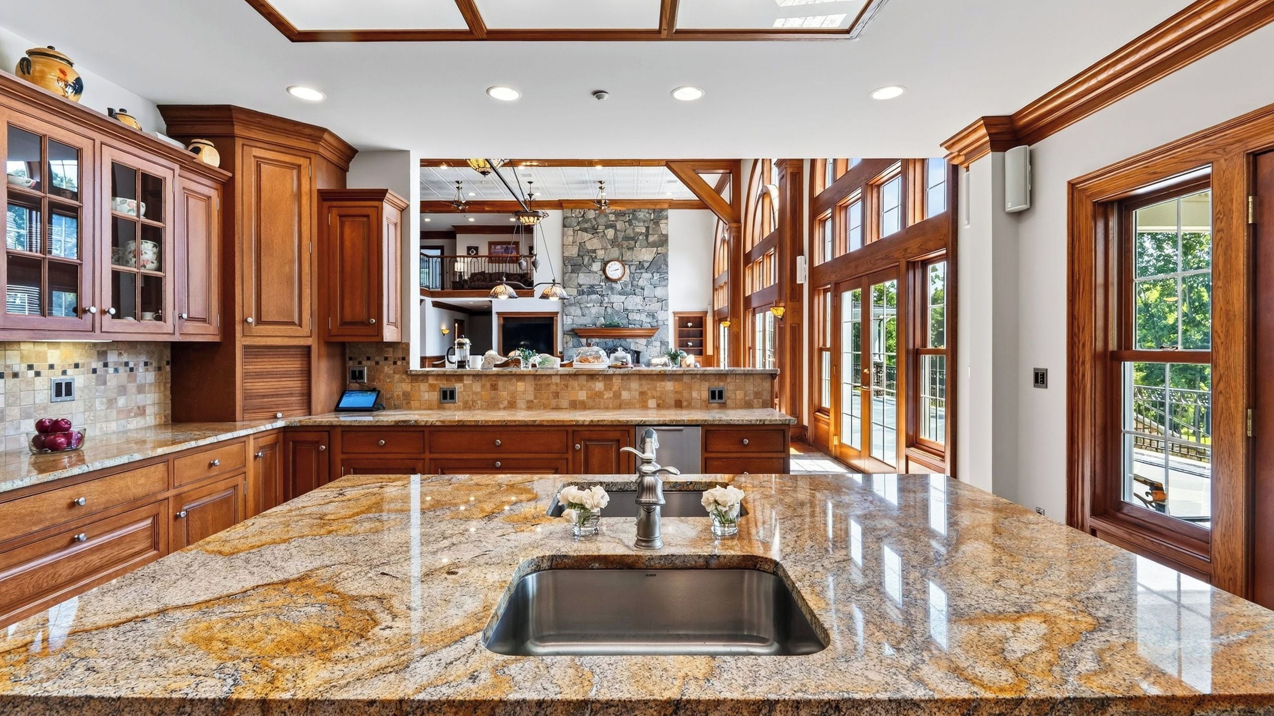 A spacious kitchen with granite countertops, wooden cabinets, and a large island with a sink.
