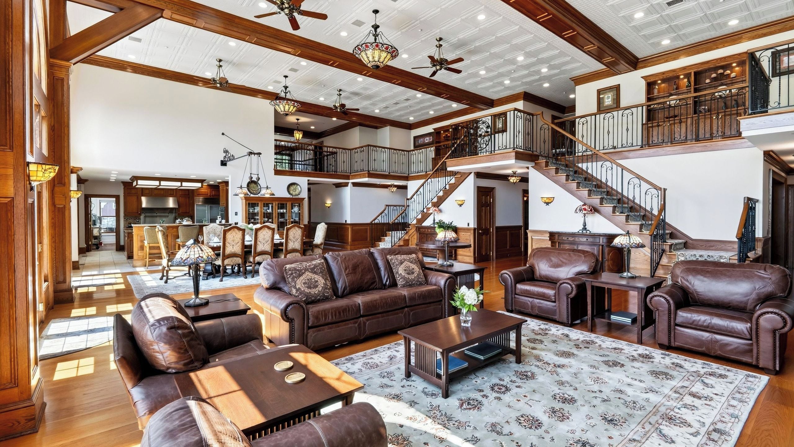 A spacious living room with leather sofas, a coffee table, and a staircase leading to an upper level.
