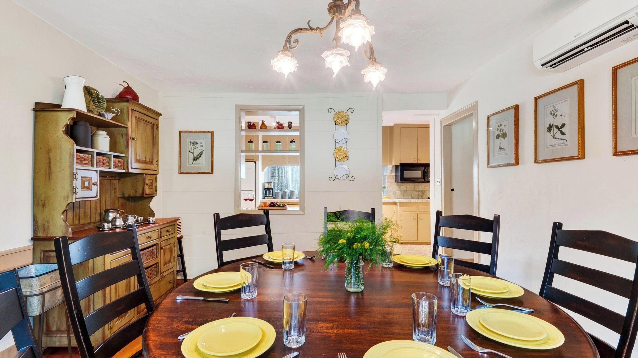 A dining room with a wooden table set for six, surrounded by chairs.
