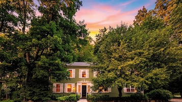 A two-story house with a front porch, surrounded by dense trees.