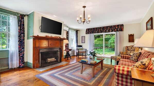 A living room with a fireplace, a television, a sofa, and a dining table. - Preston House by Avantstay Book-lined Library + Sunroom + Dining for 8 Near Hiking Trails + Metro-north (Dover Plains)