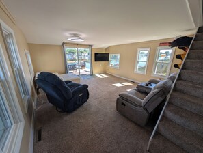 A living room with a sofa, a recliner, a TV, and a view of a pool through a sliding glass door. - Serene 2-bedroom lakeside waterfront cottage getaway in Michigan Center (Michigan Center)