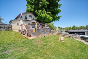A house with a deck, a wooden fence, and a large tree. - Serene 2-bedroom lakeside waterfront cottage getaway in Michigan Center (Michigan Center)