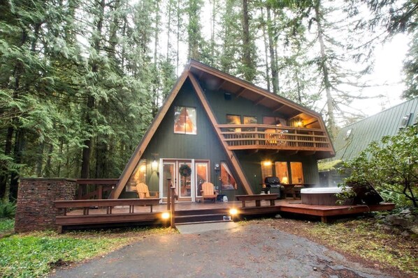 A cabin with a wooden deck, a hot tub, and a fireplace.
