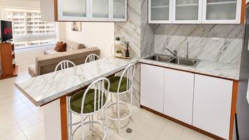 A modern kitchen with white cabinets, a marble countertop, and a built-in sink.