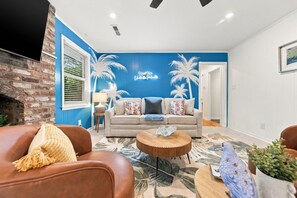 Ein Wohnzimmer mit blauer Akzentwand, einem Kamin, einem Sofa und einem Couchtisch.