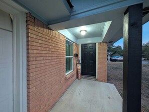 Une façade en briques avec une porte et un petit espace porche.