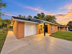 A modern single-story house with a garage, a covered porch, and a well-maintained lawn. - Aggieland Retreat - 4BR/3BR  Sleeps 11 Near A&M & Kyle field (College Station)