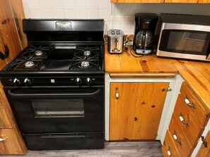 Une cuisine avec un four noir, un grille-pain, une machine à café et un four à micro-ondes.