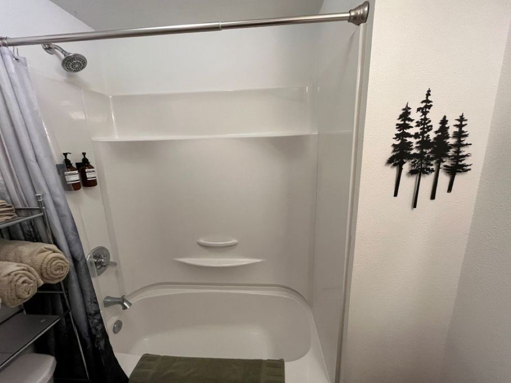 A shower area with a glass door, a towel rack with towels, and a shelf.