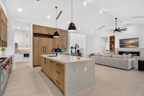 A modern kitchen with wooden cabinets, a central island, and pendant lighting.