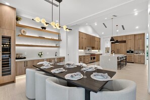 A modern kitchen with wooden cabinets, a central island, and a dining area set for six.