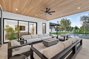 A modern outdoor living area with a sectional sofa, a fire pit, and a poolside view. - NEW 2026 Scottsdale Resort Pickleball,Golf, Basketball, Batting Cage, pool & BBQ (Scottsdale)