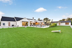 A modern house with a swimming pool, a covered patio, and a well-maintained lawn. - NEW 2026 Scottsdale Resort Pickleball,Golf, Basketball, Batting Cage, pool & BBQ (Scottsdale)