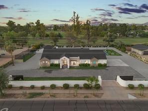 A modern two-story building with a flat roof, surrounded by a parking lot and greenery. - NEW 2026 Scottsdale Resort Pickleball,Golf, Basketball, Batting Cage, pool & BBQ (Scottsdale)