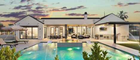 A modern house with a swimming pool, outdoor seating, and a patio area.