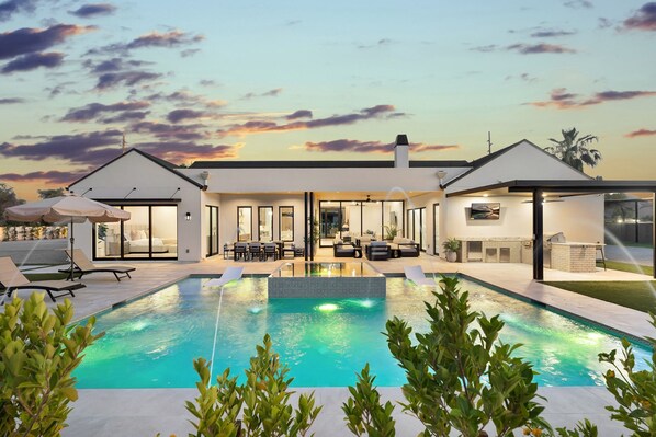 A modern house with a swimming pool, outdoor seating, and a patio area.