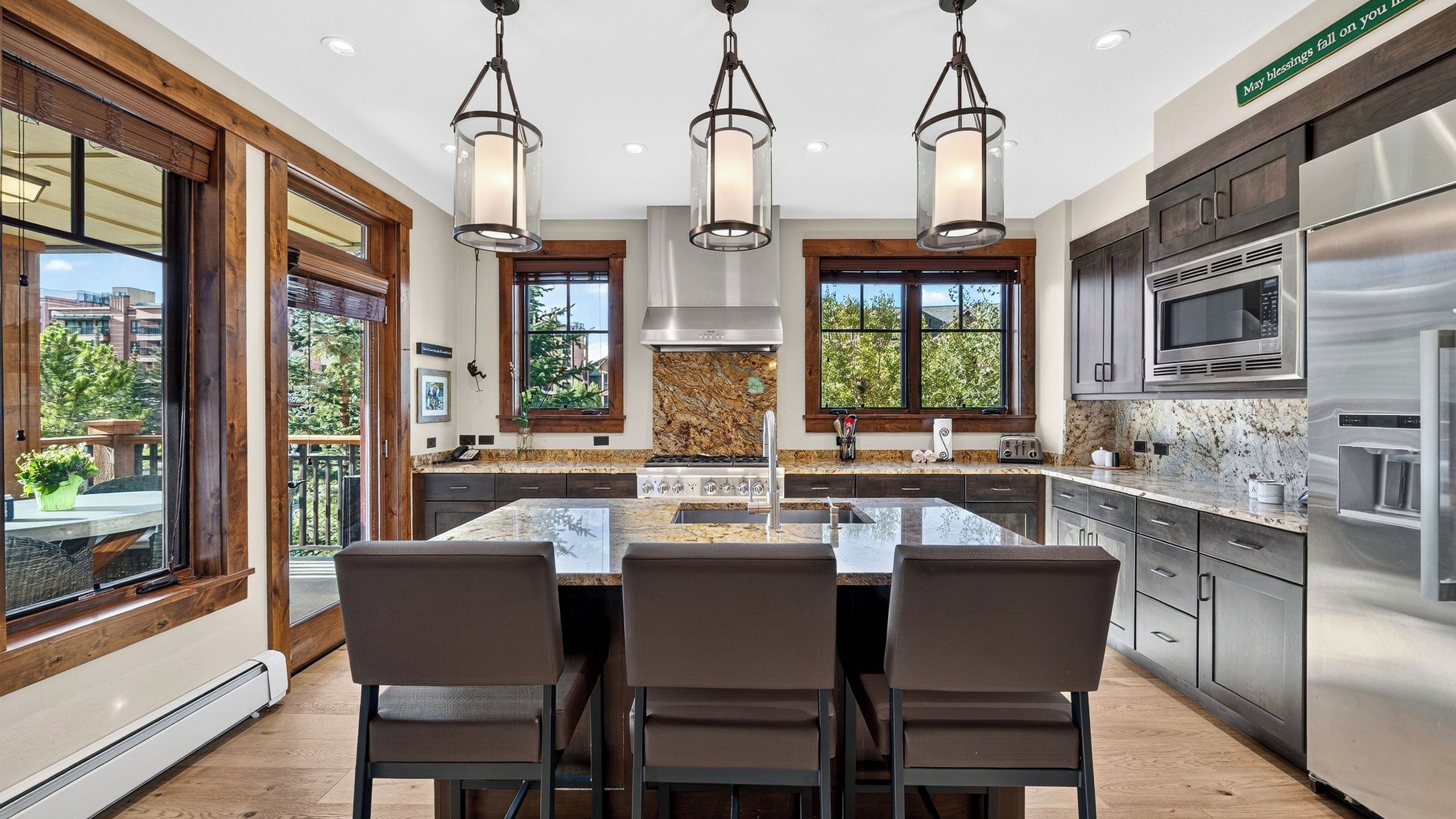 A modern kitchen with a central island, stainless steel appliances, and pendant lighting.