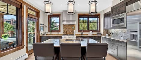 A modern kitchen with a central island, stainless steel appliances, and pendant lighting.