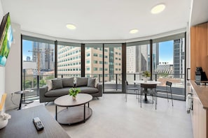 A modern living room with a sofa, a coffee table, and a dining area with chairs. - 501 First Corner Loft Balcony & City Views (Miami)